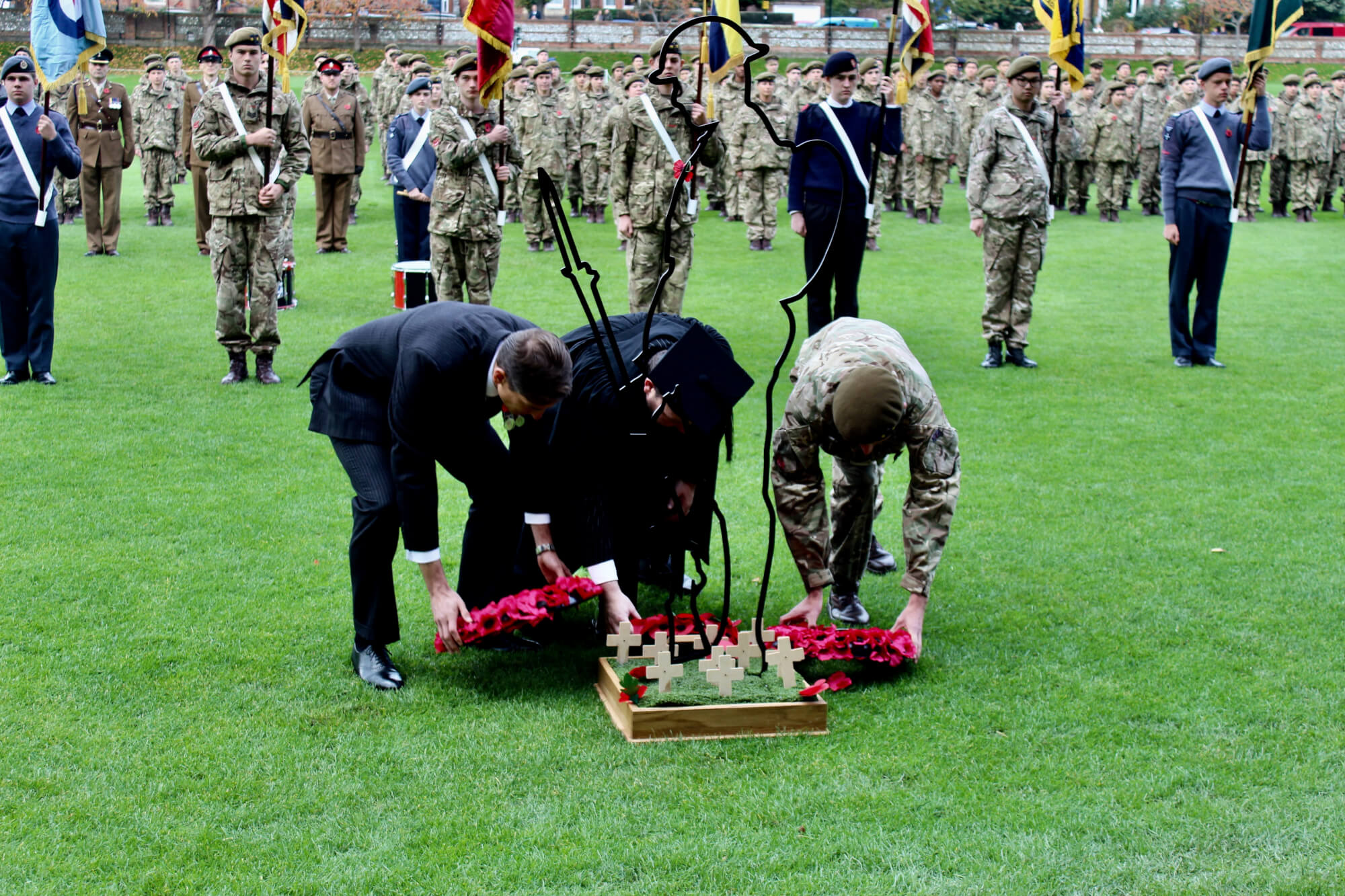 left to right: captain mark harris, the headmaster and a pupil lay wreaths at the feet of the fallen soldier